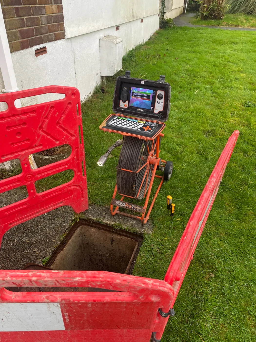 CCTV drainage survey camera set up with safety barriers around the inspection chamber